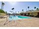 Community pool with lounge chairs, sun umbrellas, and palm trees, creating a relaxing oasis for residents at 318 S Crismon Rd # 83, Mesa, AZ 85208