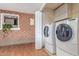 Utility room featuring washer/dryer, white bi-fold doors, brick walls and window with growing green plant at 3607 N 21St Ave, Phoenix, AZ 85015