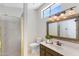 Well-lit bathroom features a vanity with decorative mirror and a glass-enclosed shower at 4066 E Grandview St, Mesa, AZ 85205