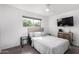 Carpeted bedroom with ceiling fan, natural light, and mounted television at 5525 E Thomas Rd # K6, Phoenix, AZ 85018