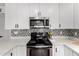 Kitchen featuring stainless steel oven/stove with black top and microwave, mosaic tile backsplash, and white countertops at 5525 E Thomas Rd # K6, Phoenix, AZ 85018