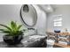 Modern bathroom featuring a round mirror, marble countertop, and stylish plant accents at 6527 W Bloomfield Rd, Glendale, AZ 85304