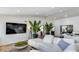 Bright living room featuring a plush sofa, large TV, and stylish indoor plants at 6527 W Bloomfield Rd, Glendale, AZ 85304