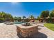 Entertaining backyard with stone fire pit, lush landscaping, and swimming pool at 6963 W Aurora Dr, Glendale, AZ 85308
