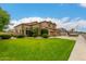 Well-manicured front lawn leading to a two-story home featuring a three-car garage at 6963 W Aurora Dr, Glendale, AZ 85308