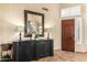 Elegant foyer with a dark wood cabinet and ornate mirror reflecting the staircase at 6963 W Aurora Dr, Glendale, AZ 85308