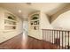 Upstairs hallway featuring hardwood floors, arched display shelves, and a staircase at 6963 W Aurora Dr, Glendale, AZ 85308