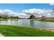 Peaceful community pond with surrounding homes and well-maintained grassy shoreline on a sunny day at 6963 W Aurora Dr, Glendale, AZ 85308