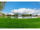 Scenic community pond surrounded by lush green grass and mature trees under a bright blue sky at 6963 W Aurora Dr, Glendale, AZ 85308