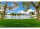Picturesque view of community pond framed by mature trees and vibrant green lawn on a sunny day at 6963 W Aurora Dr, Glendale, AZ 85308