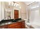 Bright bathroom featuring granite countertops, a shower-tub combo, and a framed dark wood cabinet at 7009 E Acoma Dr # 2134, Scottsdale, AZ 85254