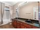 Bathroom with double sink vanity, granite countertops, dark wood cabinets, and tiled shower and flooring at 7009 E Acoma Dr # 2134, Scottsdale, AZ 85254
