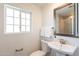Bright bathroom features a pedestal sink, decorative mirror, and a window providing natural light at 726 W El Camino W Dr, Phoenix, AZ 85021