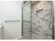 Modern shower with stylish gray marble tiling, a sliding glass door, and a convenient inset shelf at 8401 N 84Th Pl, Scottsdale, AZ 85258