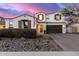 Charming two-story home featuring a red tile roof, stone landscaping, and a three-car garage at 9544 E Theia Dr, Mesa, AZ 85212