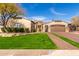 Stunning home featuring lush lawn, mature trees, an arched entry, and a spacious three-car garage at 9834 E Voltaire Dr, Scottsdale, AZ 85260