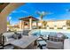 Inviting pool area with a shaded outdoor kitchen, a bar, comfortable seating, and lush palm trees at 9834 E Voltaire Dr, Scottsdale, AZ 85260