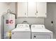 Bright laundry room features washer, dryer, water heater, and storage cabinets at 9926 W Lancaster Dr, Sun City, AZ 85351