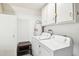 Bright laundry room with a white washer, white dryer, and white cabinets at 9926 W Lancaster Dr, Sun City, AZ 85351