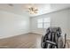 A bright bedroom with wood-look flooring, ceiling fan, window and black massage chair at 1189 E Tyler Ln, Casa Grande, AZ 85122
