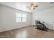 A bright bedroom featuring wood-look floors, ceiling fan, window and dark massage chair at 1189 E Tyler Ln, Casa Grande, AZ 85122