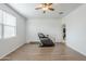A bright bedroom featuring wood-look floors, ceiling fan, window and dark massage chair at 1189 E Tyler Ln, Casa Grande, AZ 85122
