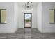 Elegant foyer with soaring ceilings, modern chandelier, and view of the desert through glass front door at 14902 W Oberlin Way, Surprise, AZ 85387