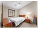 Cozy bedroom with a bed, nightstand, dresser, wood-framed window, and ceiling fan at 1559 E Peregrine Trl, Casa Grande, AZ 85122
