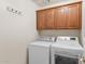Convenient laundry room featuring a washer, dryer, and overhead storage cabinets at 1559 E Peregrine Trl, Casa Grande, AZ 85122
