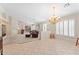 Open-concept living room with carpeted and tiled flooring, large windows and decorative chandelier at 1559 E Peregrine Trl, Casa Grande, AZ 85122