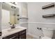 A well lit bathroom featuring a vanity, mirror, shelving, and a toilet at 17406 N 28Th Dr, Phoenix, AZ 85053