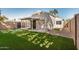 A charming property boasting a spacious, fenced backyard with verdant faux grass and shaded patio area at 17406 N 28Th Dr, Phoenix, AZ 85053