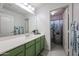 Bathroom featuring a large mirror, single sink vanity, and a shower with floral curtains at 17687 W Surrey Dr, Surprise, AZ 85388
