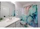 Clean bathroom with a decorative shower curtain, patterned toilet seat, and a modern sink at 17687 W Surrey Dr, Surprise, AZ 85388