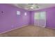 Bedroom painted purple featuring a ceiling fan, windows, and carpeted flooring at 17687 W Surrey Dr, Surprise, AZ 85388