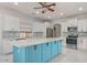Modern kitchen featuring white cabinetry, stainless steel appliances, a stylish blue island, and a complementary backsplash at 17687 W Surrey Dr, Surprise, AZ 85388