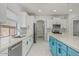 Modern kitchen featuring white cabinetry, stainless steel appliances, a stylish blue island, and a complementary backsplash at 17687 W Surrey Dr, Surprise, AZ 85388