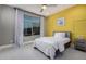Cozy bedroom with a soft carpet, a large window with white curtains, and a yellow accent wall at 1936 W Kinfield Trl, Phoenix, AZ 85085