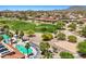 Aerial view showcases a pool, tennis courts, and golf course with mountain views at 22419 W La Pasada Blvd, Buckeye, AZ 85326
