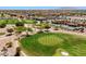 Scenic aerial view of a golf course with mature trees, a clubhouse, and community pool at 22419 W La Pasada Blvd, Buckeye, AZ 85326
