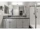 Bright bathroom featuring a granite countertop vanity with dual sinks and a glass enclosed shower at 22419 W La Pasada Blvd, Buckeye, AZ 85326