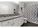 Bright bathroom featuring a granite countertop vanity with dual sinks and a shower with patterned curtain at 22419 W La Pasada Blvd, Buckeye, AZ 85326