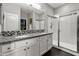 Bright bathroom featuring a granite countertop vanity with dual sinks and a glass enclosed shower at 22419 W La Pasada Blvd, Buckeye, AZ 85326