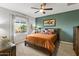 Charming bedroom features a ceiling fan, large window, and a wooden bed frame with colorful pillows at 22419 W La Pasada Blvd, Buckeye, AZ 85326