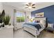 Comfortable bedroom with a ceiling fan, large window, and a queen bed with blue accents at 22419 W La Pasada Blvd, Buckeye, AZ 85326