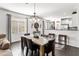 Elegant dining room with modern chandelier, large window, and dark wood floors adjacent to the kitchen at 22419 W La Pasada Blvd, Buckeye, AZ 85326