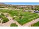 Aerial view of the lush green golf course with desert landscape and mountain views at 22419 W La Pasada Blvd, Buckeye, AZ 85326