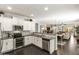 Open-concept kitchen with stainless steel appliances, white cabinetry, granite countertops, and dark wood floors at 22419 W La Pasada Blvd, Buckeye, AZ 85326