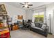 Bright home office featuring a ceiling fan, large window, desk setup, and a comfortable gray couch at 22419 W La Pasada Blvd, Buckeye, AZ 85326