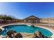 Backyard pool with rock waterfall feature and fenced perimeter, nestled within desert landscaping and providing privacy at 22727 W Papago St, Buckeye, AZ 85326